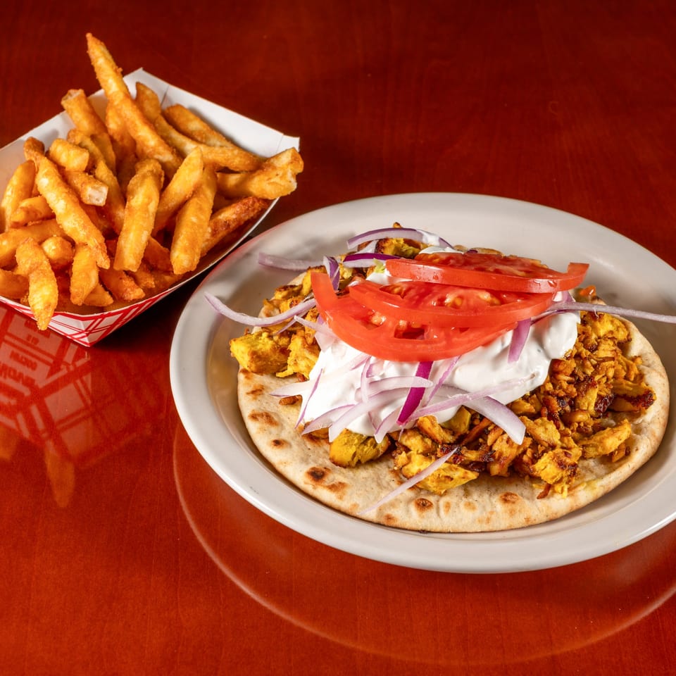 Cedar Grill's chicken shawarma on pita with tomatoes, onions, and sauce, served with fries.