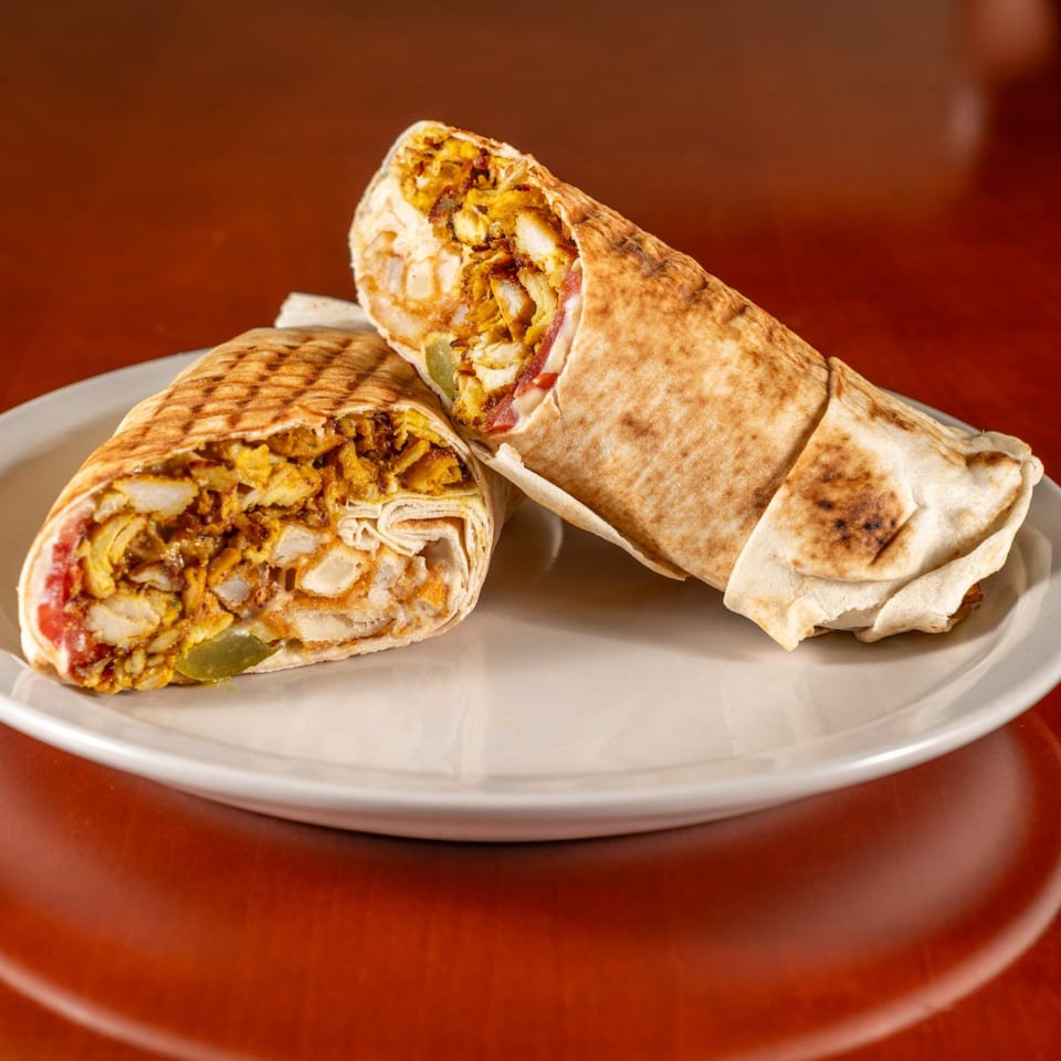 Two Cedar Grill chicken shawarma wraps, one cut in half, on a white plate.